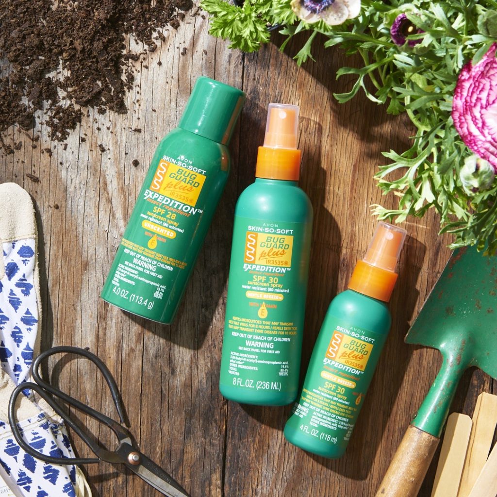 Bottles of all three products in the Bug Guard Plus IR3535 insect repellant line artistically laid on a wooden surface, surrounded by gardening supplies
