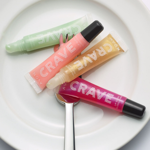 4 tubes of Crave Lip Gloss artistically strewn on a white plate with a silver fork