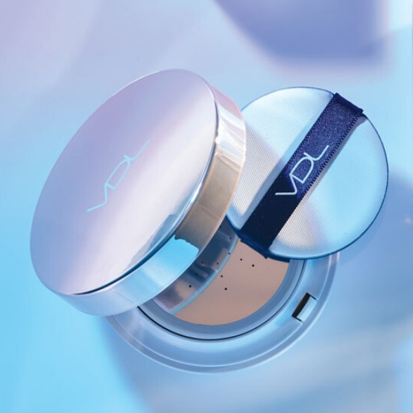 Slightly open compact of Lumilayer Metal cushion primer, against a blue and purple background