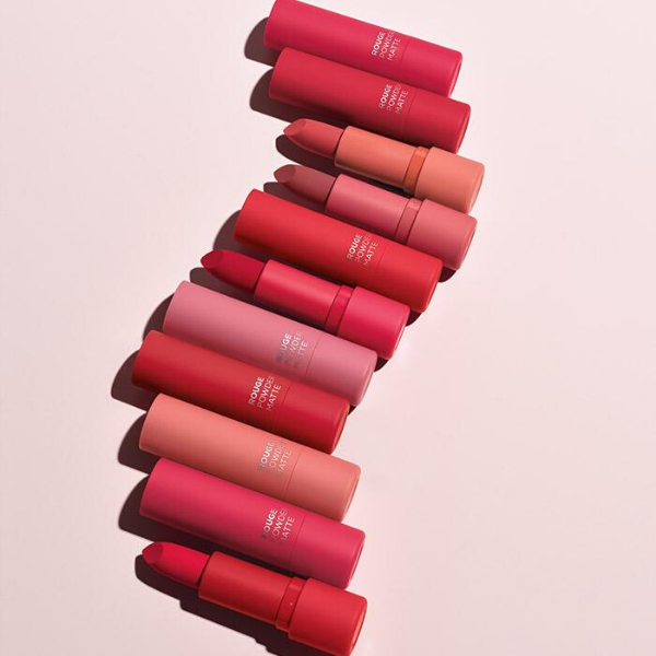 11 tubes of rouge powder lipstick arranged in a curved line, against a light pink background