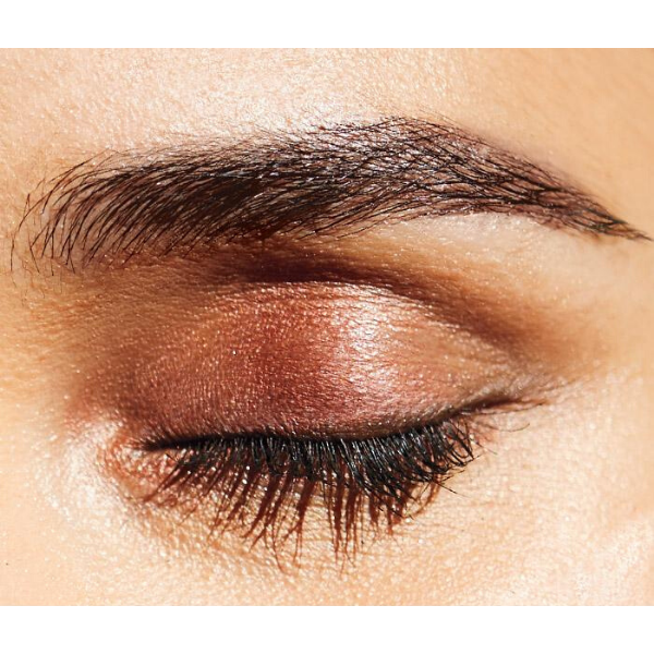 Close up of a woman's closed eye with golden brown eyeshadow, prow pomade, and mascara