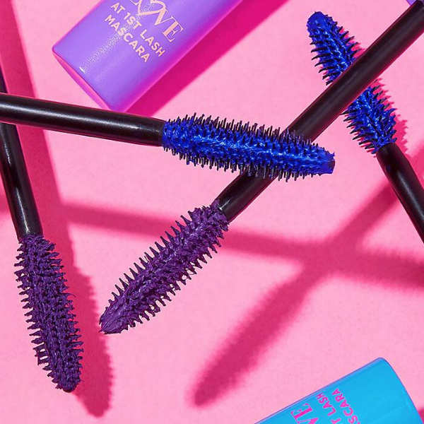 Mascara wands from the Electric Lash Love at 1st Lash Mascara artistically strewn against a pink background