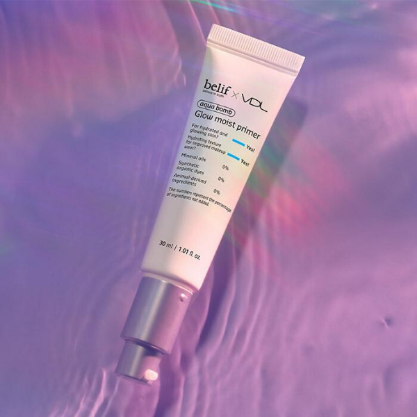 Tube of belif x VDL Glow Moist Primer in front of a water-filled, purple background
