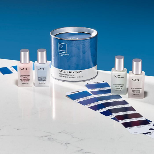 Contents of the VDL X Pantone Primer Mini Kit artistically strewn on a marble table, next to blue paint color sample cards