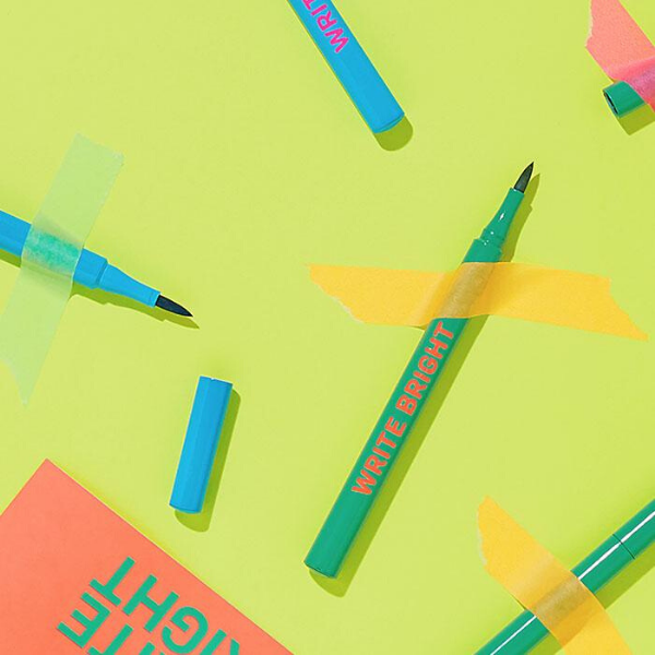 Tubes of Write Bright Eyeliner artistically placed and taped onto a chartreuse background
