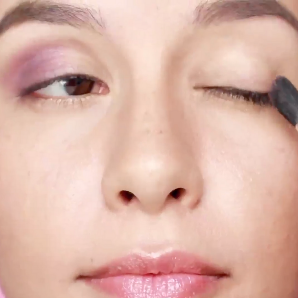 Close up of a woman's face as she applys eyeshadow to her outer lid