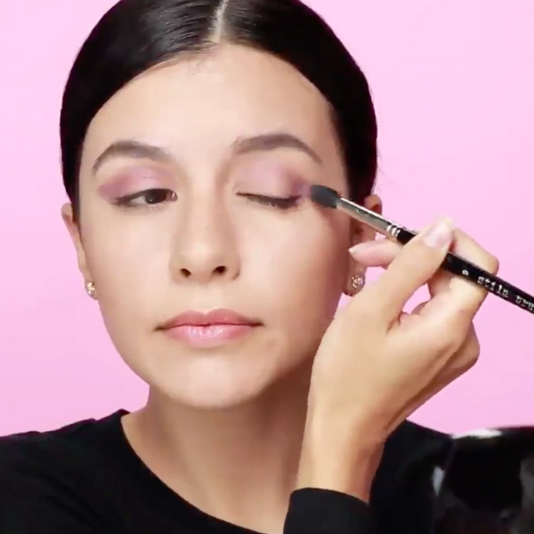 Woman in a black shirt applying eyeshadow to her outer lid