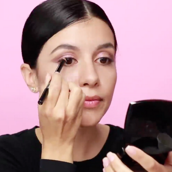 Woman in a black shirt applying eyeliner