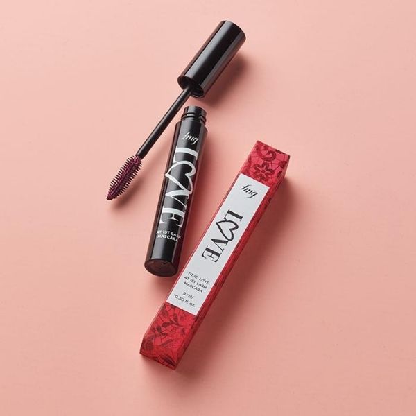 Open tube of True Love at 1st Lash Mascara in the shade Velvet Mulberry, one of Avon's Valentine's Day makeup specials, against a peach pink background