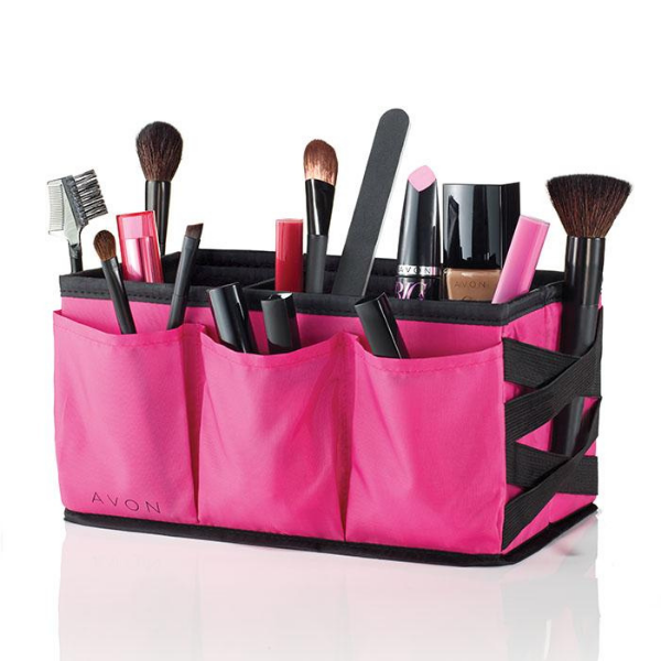 Pink colored Avon Beauty Caddy, a discontinued Avon product, filled with miscellaneous makeup products against a white background