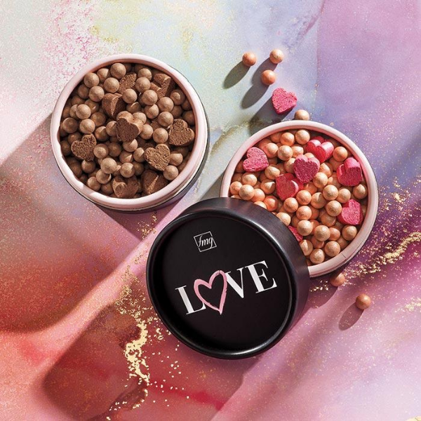 Two open containers of Colors of Love Glow Beads Illuminating Powder, sitting on a marble tie-dye background
