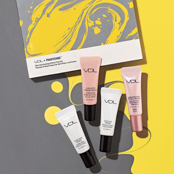 Open box of VDL Pantone Skin Illuminating Primer Trial Kit, on top of a grey and yellow surface with artistic pain swirls