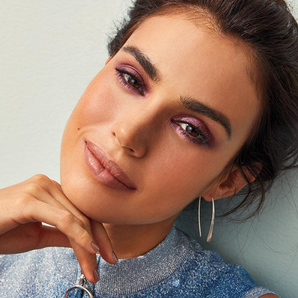 Smiling model tilting her head as she shows off the Summer Eyeshadow Palette, Lip Shine Lipstick