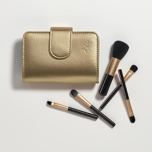 Light Golden faux-leather makeup brush case next to 5 differently sized makeup brushes, artistically strewn on a light beige surface