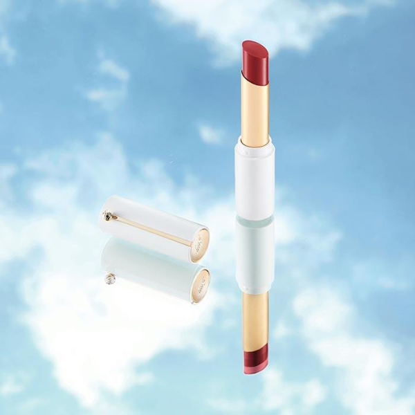 Open tube of fmgt Ink Sheer Matte Lipstick in front of a blue sky background with white clouds