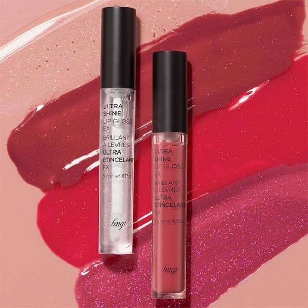 Two tubes of fmgt Ultra Shine Lip Gloss, in front of a pink background with four stripes of artistic lip gloss smears