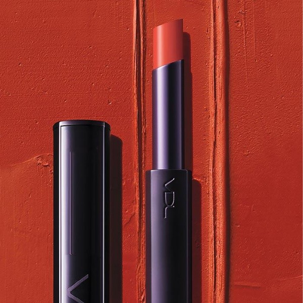 Open tube of VDL Expert Slim Lip Color Shine in front of a red background