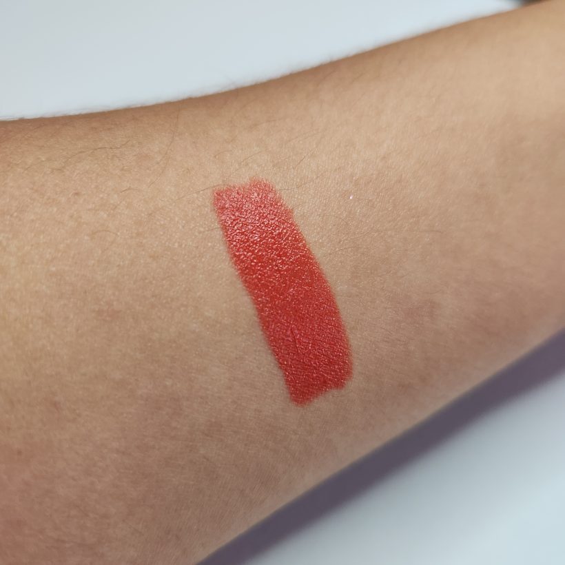 Arm swatch showing the shade Poppy in Avon's Glimmer Satin Lipstick