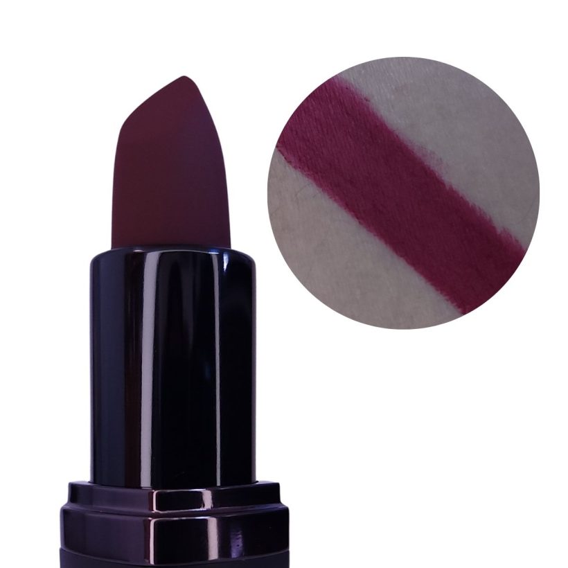 Open tube of berry purple lipstick with only the top half showing, next to a arm swatch of the same shade